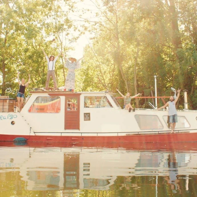 a group of friends stands on top of the original Valparaíso ship, showcasing how happy it makes them to live in community working together towards a better future, economically, socially, culturally, ecologically